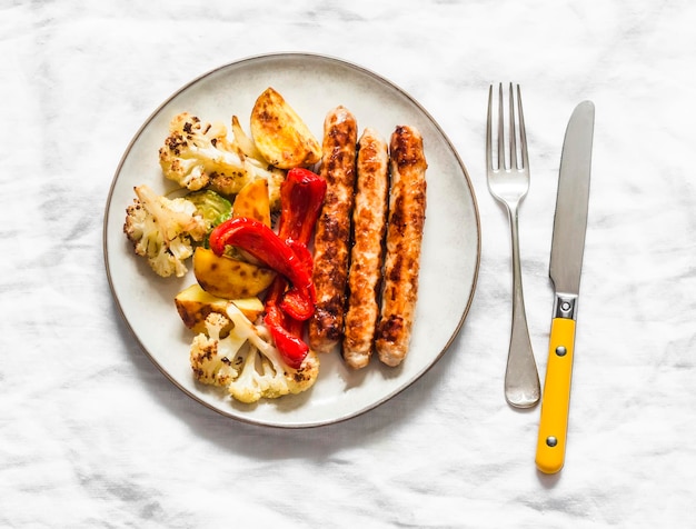 Saucisse de poulet et légumes rôtis sur une vue de dessus de fond clair