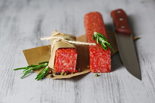 Saucisse de salami savoureuse, sur papier sur table en bois