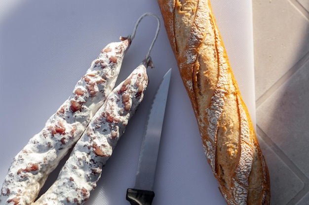 Saucisse séchée avec moisissure blanche et baguette française sur la vue de dessus de la planche à découper