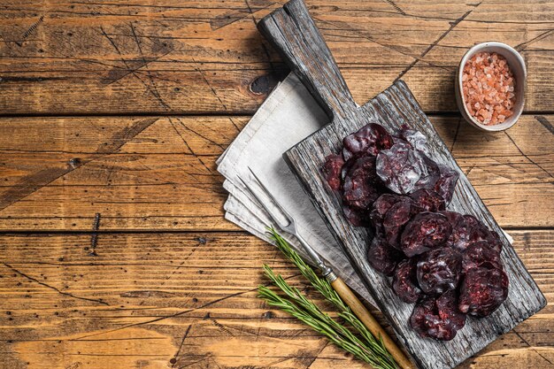 Saucisse séchée à la viande de gibier de cheval au romarin sur une planche à découper. Fond en bois. Vue de dessus. Copiez l'espace.