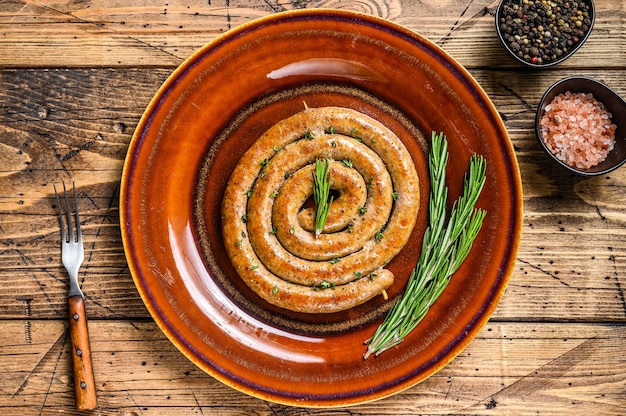 Saucisse en spirale grillée de viande de porc et de bœuf sur une assiette rustique. fond en bois. Vue de dessus.