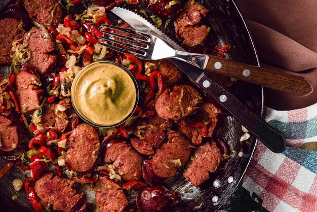 Saucisse tranchée et mélange de légumes frais frits dans la poêle rustique avec de la moutarde sur un torchon.