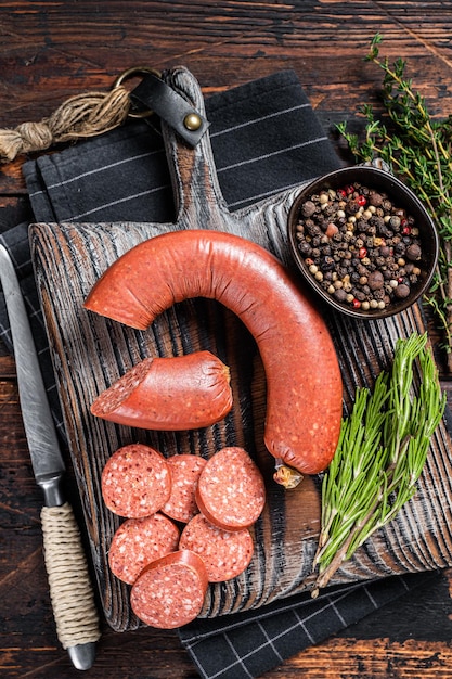 Saucisse de viande de boeuf Sucuk tranchée sur une planche à découper avec des herbes. Fond en bois. Vue de dessus.