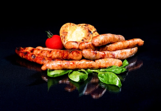 Saucisses aux légumes grillés sur un fond sombre