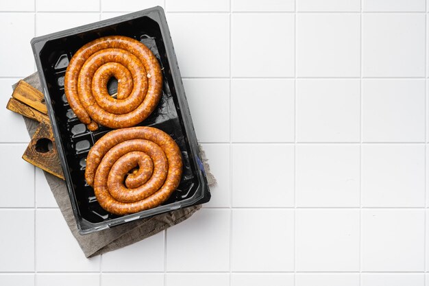 Saucisses barbecue en spirale sur fond de table en carreaux de céramique blanche vue de dessus mise à plat avec espace de copie pour le texte