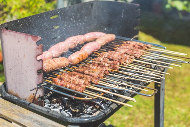 Saucisses et brochette de viande sur le brasier