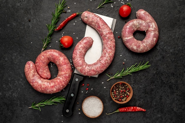 Saucisses crues aux épices sur un couteau sur un fond de pierre