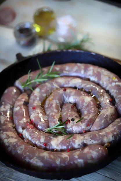 Saucisses crues aux épices dans une poêle avant la cuisson