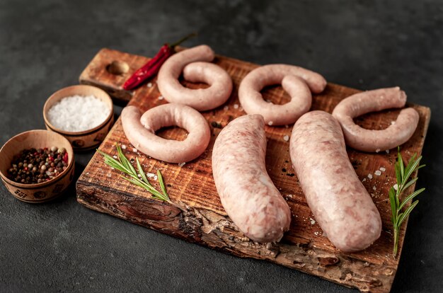 Saucisses crues aux épices et romarin, sur une table en pierre, concept de cuisine