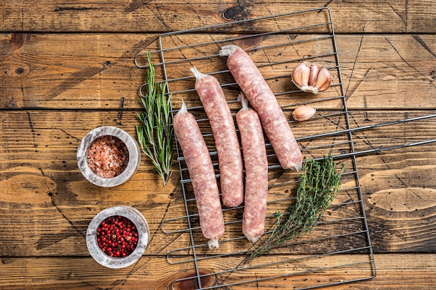 Saucisses crues - Bratwurst avec de la viande de porc sur un gril. Fond en bois. Vue de dessus.