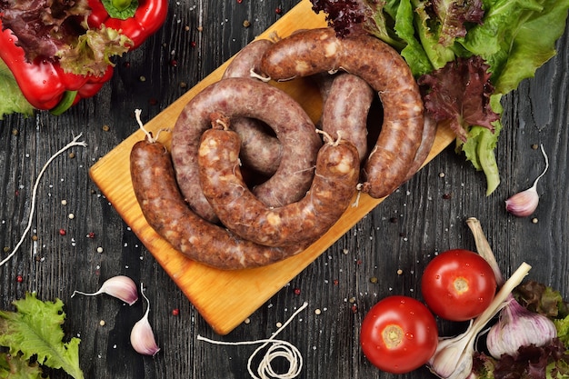 Saucisses crues fraîches sur une planche à découper. Fond en bois. Vue de dessus.