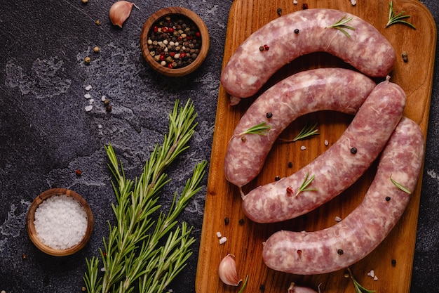 Saucisses crues et ingrédients pour cuisiner sur une table en pierre noire