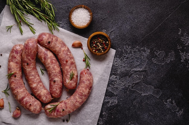 Saucisses crues et ingrédients pour cuisiner sur une table en pierre noire