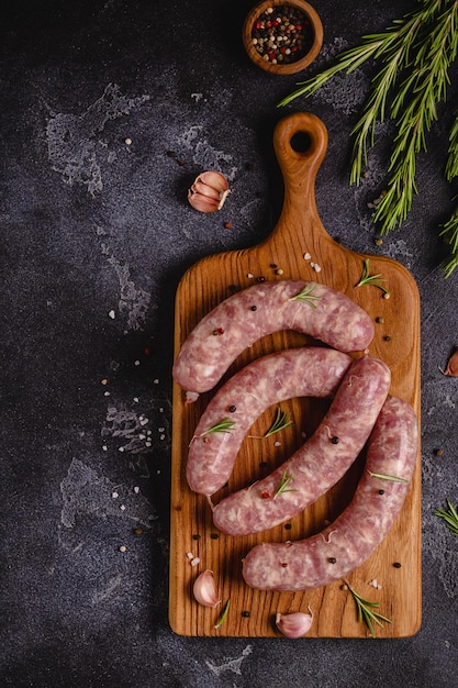 Saucisses crues et ingrédients pour cuisiner sur une table en pierre noire