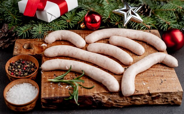 Saucisses crues sur planche de bois avec des décorations de Noël à côté