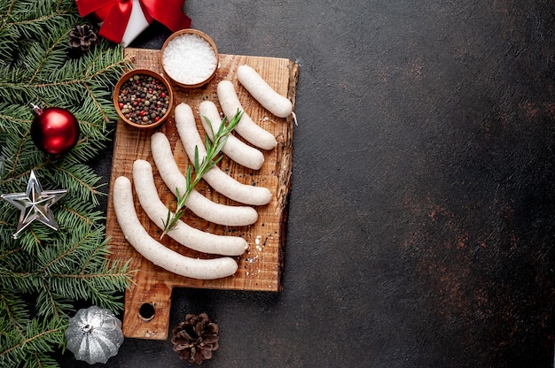 Saucisses crues sur planche de bois avec des décorations de Noël à côté