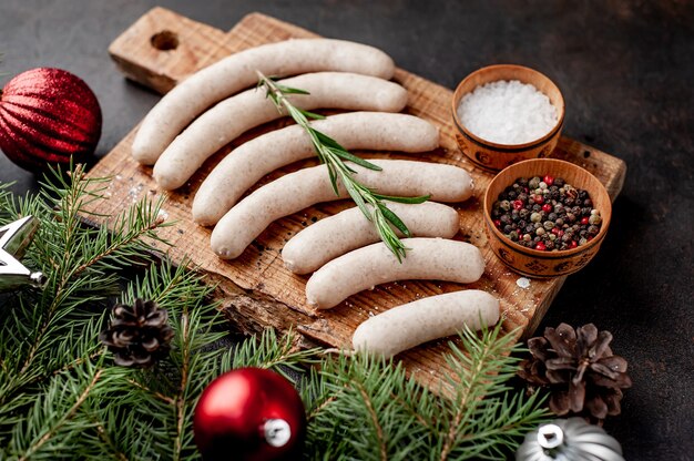 Saucisses crues sur planche de bois avec des décorations de Noël à côté