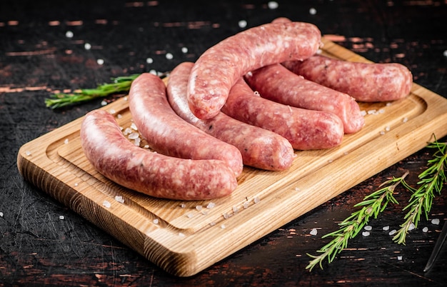 Saucisses crues sur une planche à découper avec un brin de romarin