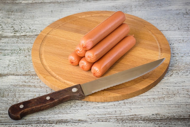 Saucisses crues sur planche à découper sur fond de bois rustique blanc