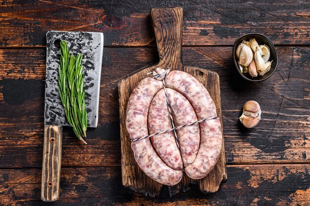 Saucisses crues de viande de porc et de boeuf sur la planche à découper en bois