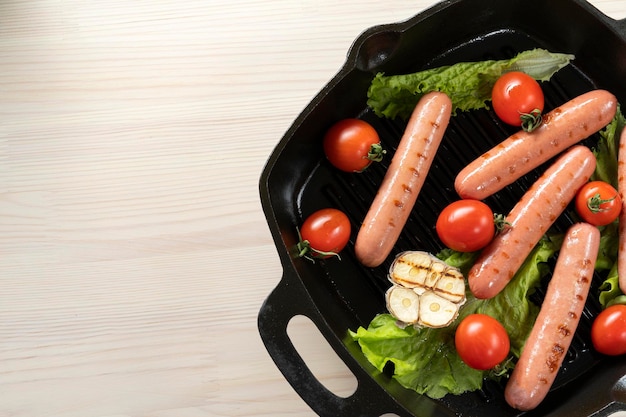 Saucisses dans une poêle en fonte avec tomates laitue ail frit vue de dessus espace de copie