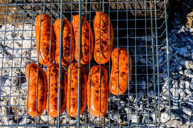 Saucisses faisant cuire dans un gril de barbecue sur le feu de camp