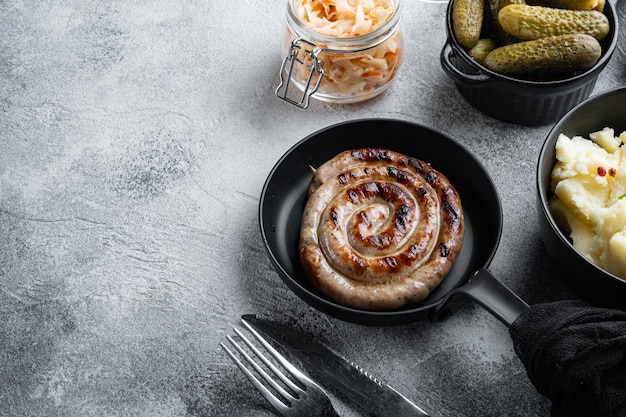 Saucisses frites bavaroises sur choucroute dans une poêle en fonte, sur fond gris , avec un espace pour le texte