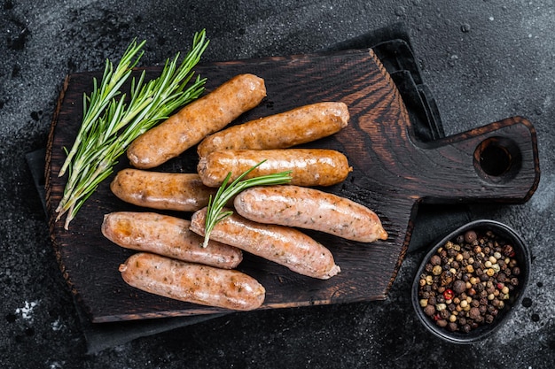 Saucisses frites Bratwurst ou Hot Dogs sur une planche de bois. Fond noir. Vue de dessus.