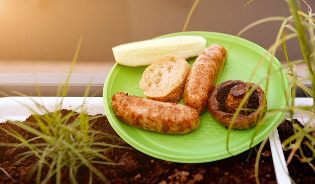 Saucisses frites pain aux champignons sur assiette jetable nature pique-nique. photo de haute qualité