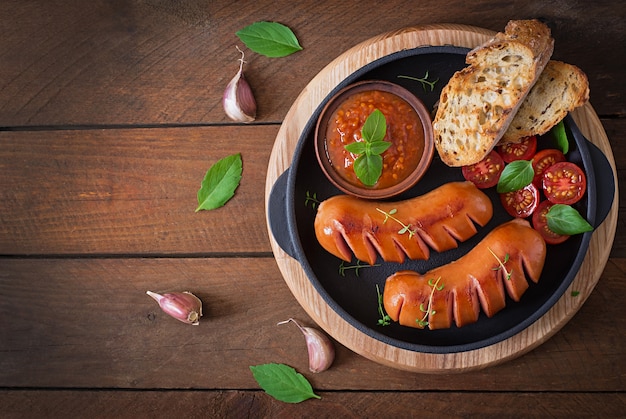 Saucisses sur le gril sur la table en bois