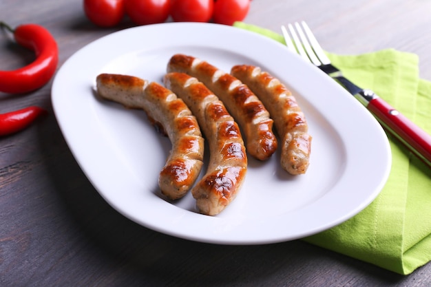 Photo saucisses grillées sur une assiette avec des légumes sur la table en gros plan