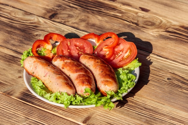 Saucisses grillées aux légumes frais sur table en bois