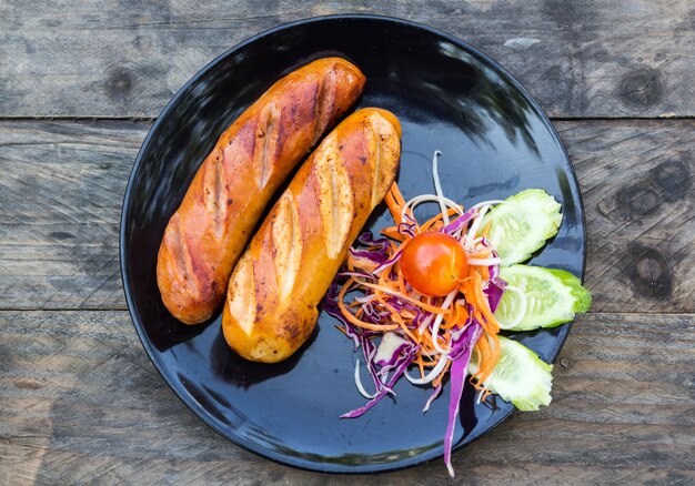 saucisses grillées et légumes dans un plat noir