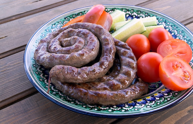 Saucisses grillées avec des légumes frais sur une table en bois.