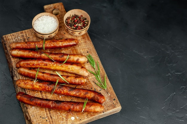 saucisses grillées sur une planche à découper avec des épices et du romarin sur une table en pierre avec copie espace pour votre texte