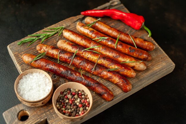 saucisses grillées sur une planche à découper avec des épices et du romarin sur une table en pierre