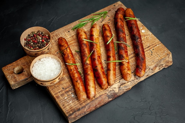 saucisses grillées sur une planche à découper avec des épices et du romarin sur une table en pierre