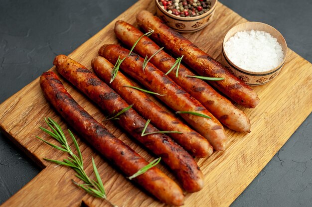 saucisses grillées sur une planche à découper avec des épices et du romarin sur une table en pierre