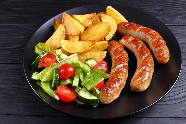 Saucisses grillées, pommes de terre au four et salade de légumes