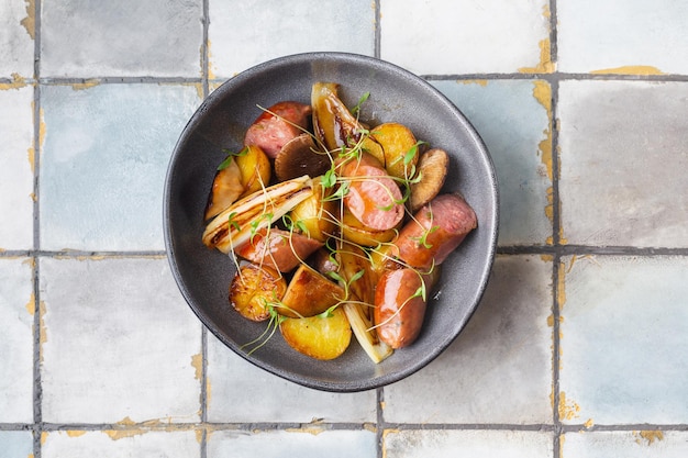 Saucisses grillées avec pommes de terre et herbes sur fond de tuile vue de dessus de la viande photo de haute qualité