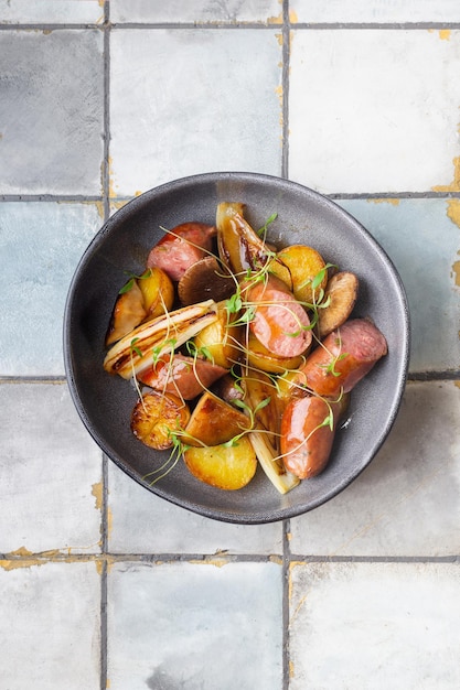 Saucisses grillées avec pommes de terre et herbes sur fond de tuile vue de dessus de la viande photo de haute qualité