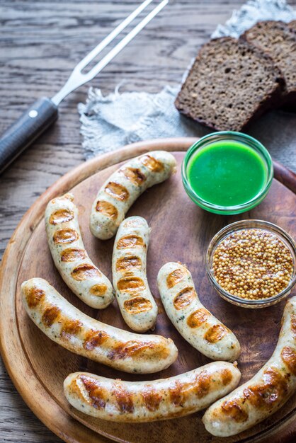 Saucisses grillées avec sauces piquantes sur planche de bois