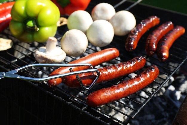 Photo des saucisses et des légumes sur le gril en gros plan