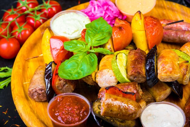 Photo saucisses maison ruddy dorées à chaud sur un plateau en bois avec des sauces et des légumes