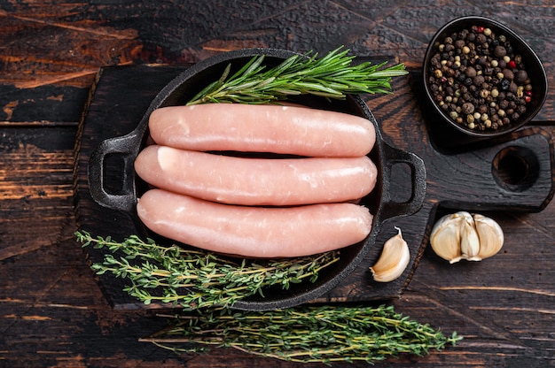 Saucisses de porc crues dans une casserole avec des herbes