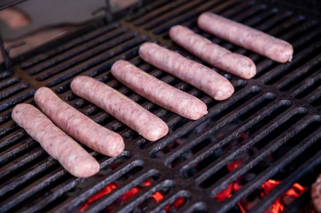 Saucisses de porc crues grillées au barbecue sur un pique-nique d'été
