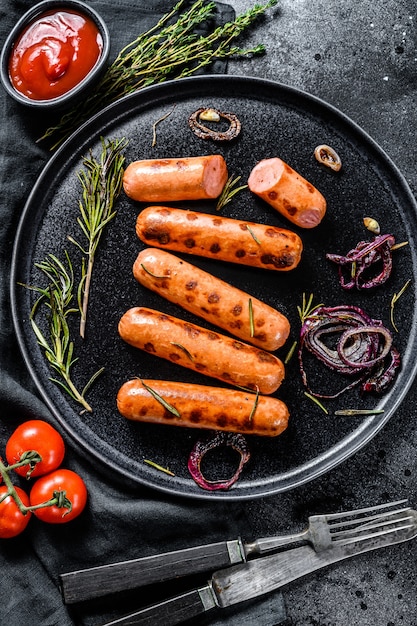 Saucisses de porc grillées à l'oignon, à l'ail et au romarin. Fond noir. Vue de dessus