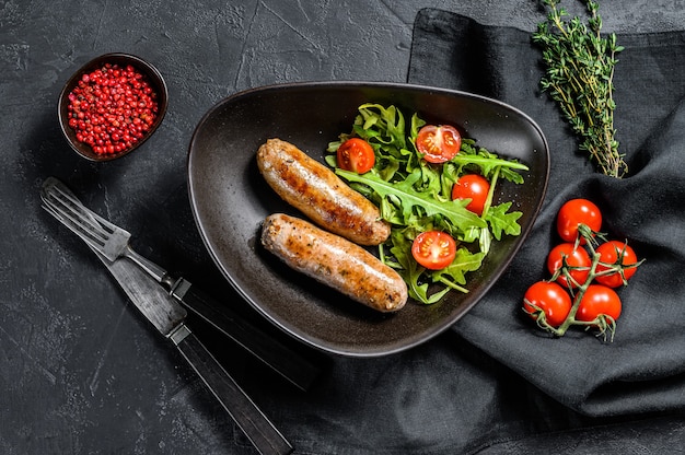 Saucisses de porc grillées avec salade de tomates et roquette