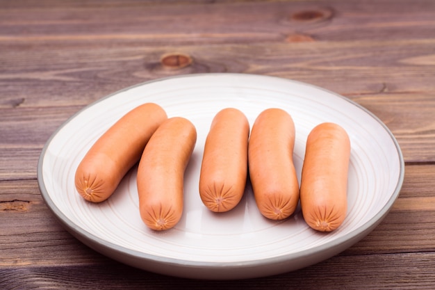 Saucisses de poulet bouillies prêtes à manger sur une assiette sur une table en bois