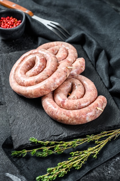 Saucisses de poulet en spirale crues traditionnelles. Fond noir.